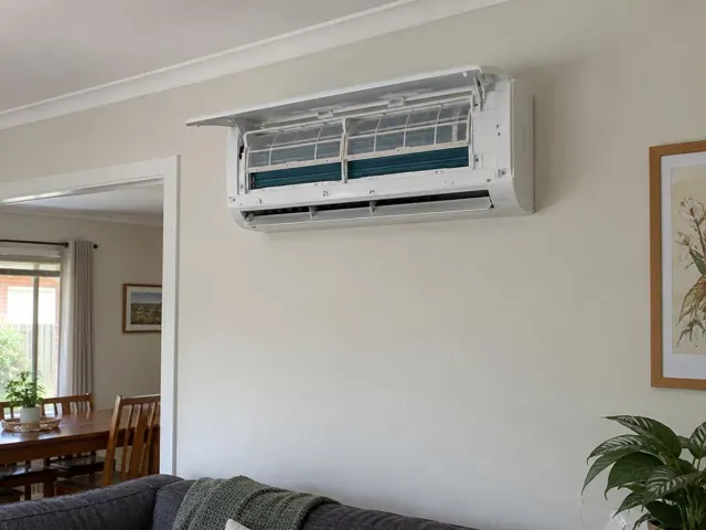 Clean split system indoor unit on a living room wall with open front panel and visible filters in Blackwood