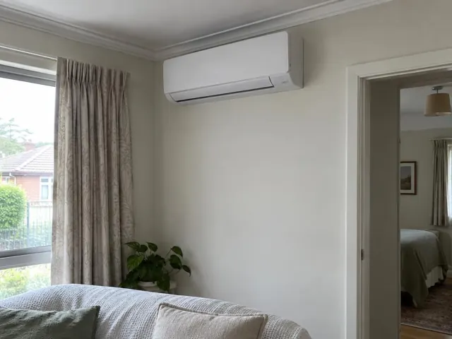 Wall-mounted split system above a bedroom wall opening with curtains and a window in Mitcham